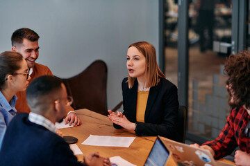 In the vibrant ambiance of a modern startup office, a diverse team of business professionals engage in discussions on various projects and develop new business strategies, epitomizing creativity and