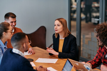 In the vibrant ambiance of a modern startup office, a diverse team of business professionals engage in discussions on various projects and develop new business strategies, epitomizing creativity and