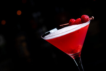 Summer red  cocktail with gin, raspberry syrup, lime juice, quail egg white and ice in glass. Black bar counter background