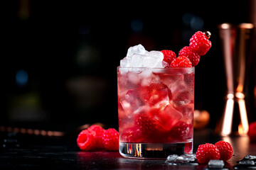 Summer alcoholic cocktail with mashed raspberries, gin, vodka, soda, and crushed ice, black...