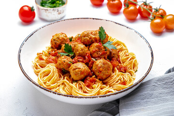 Spaghetti with meatballs in marinara sauce, top view, white table