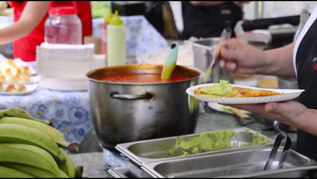 Fried platanos and avocado sauce on plate 
at street food festival.