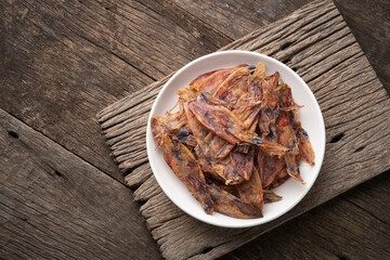 Sun dried squid on white plate on wooden table.Top view.Preserve food