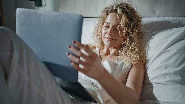 Woman looking computer bedroom in sunlight closeup. Happy girl enjoying movie
