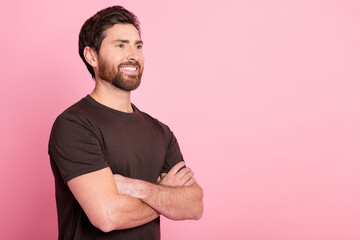Photo of toothy beaming man with stylish bristle dressed brown t-shirt arms folded look empty space isolated on pink color background