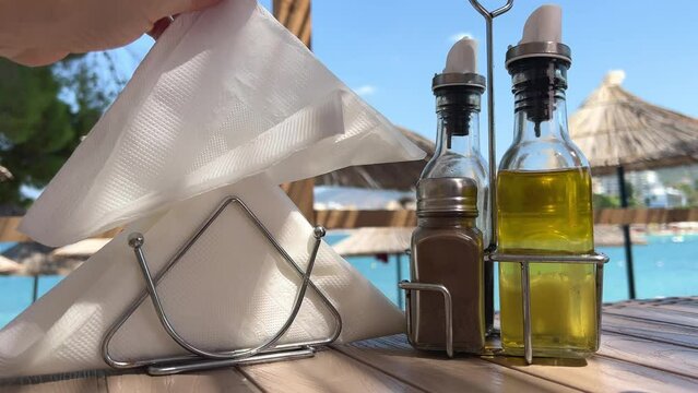  A woman pulls napkins from a napkin holder. Taking napkin on table near sea