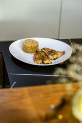 Fish dish - baked fish fillet with boiled white rice on white plate