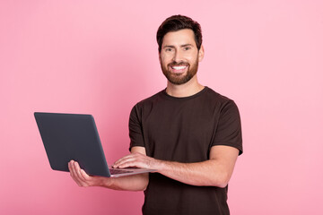Portrait of optimistic positive man with stylish bristle wear brown shirt holding laptop read email isolated on pink color background