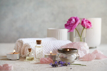 Bottles of aromatherapy essential oil with lavender and Provence rose flowers, rose quartz stones and white spa towels