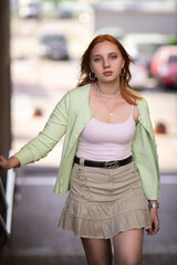 Portrait of a young beautiful red-haired girl in an urban environment.