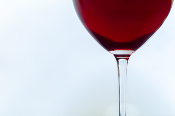 Glass of red wine close-up on white background with light reflections in natural conditions