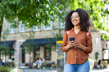 Smiling woman tourist walking in city on vacation using smartphone