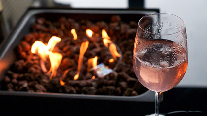 Stone firepit with fire flames and glass of wine. Summer camping bonfire.