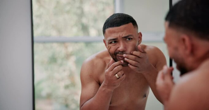 Mirror, beauty and man pop pimple in bathroom for facial grooming, cleaning or hygiene at home. Skincare, cosmetic and male person checking blackhead, breakout or acne by reflection in apartment.