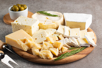 Wooden board with various cheese and olives. Brie. Camembert. Parmesan, feta, blue cheese. Italian, French cheese.