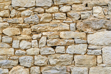 Background of a natural stone or sandstone masonry wall in South France. Detailed stone texture image in beige, brown, grey and green