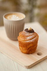 Cruffin (Kruffin)  pastry with cappuccino on the table. Minimalist style. Coffee shop lifestyle.