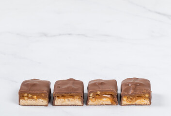 Candy bar with nougat, caramel, peanuts and hazelnuts. In  chocolate. White  background. Copy space