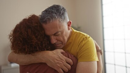 Middle-aged couple embracing in a living room showcasing love and support during an emotional moment indoors