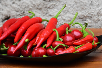 bunch of different red hot peppers on a black plate