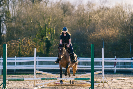 Female on horse practicing to leap over hurdle