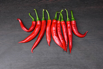 Chilli red peppers in line isolated on black wooden background. Long red hot peppers, aligned. Cayenne peppers