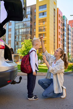 a mother drives her son to school in her car. 