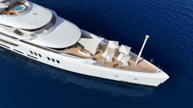 Aerial drone top down photo of luxury yacht with wooden deck anchored in deep blue Aegean sea, Mykonos island, Cyclades, Greece