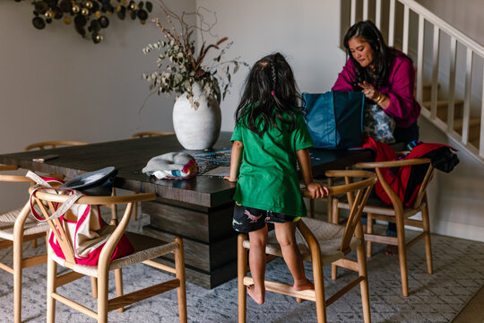 Mother packing bags at home while her daughter watches
