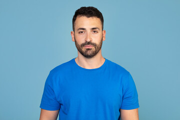 Obraz premium Portrait of handsome bearded man over blue studio background, empty space. Middle-aged bearded man posing for male magazine or blog, youth, healthy lifestyle and male cosmetology concept
