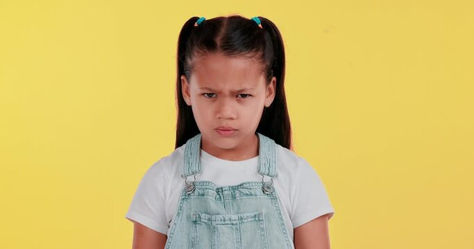 Upset, grumpy and face of child in studio with shake head no for moody, tantrum or annoyed. Angry, mad and portrait of girl kid with frustration, disagreement or attitude by yellow background.