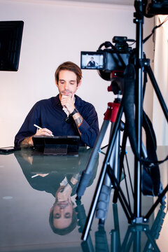 Freelance news presenter writes on an iPad while recording a video