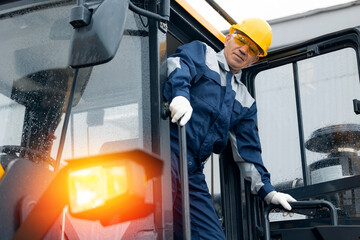 Adult man builder in hardhat operate bulldozer on mining coal, driver of excavator working at...