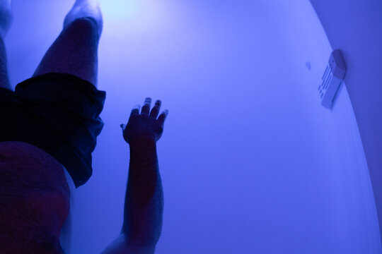 Male's hand touching a curved illuminated wall in float tank