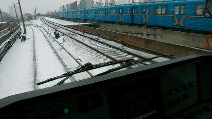 A subway train travels on rails through a snowy city. Winter in a big city.