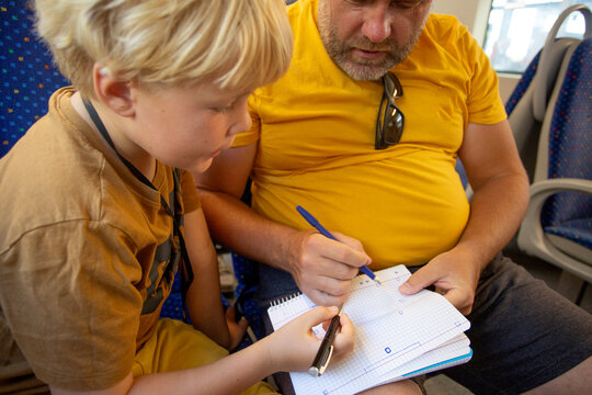 man with son playing some game on the notebook sitting on the train