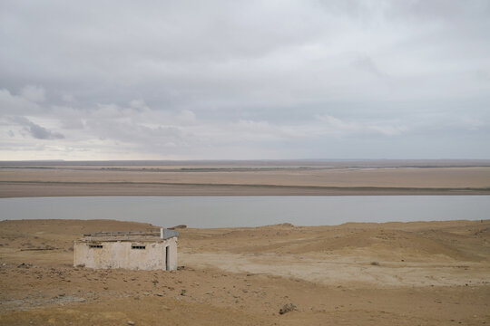 Solitary Concrete Building by a Desert River on a Cloudy Day in Remote