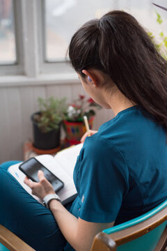 Anonymous student with technology devices and book