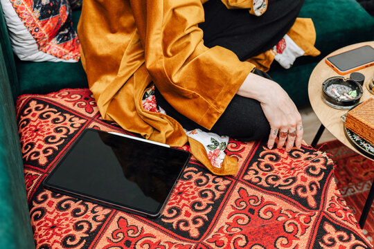 Close-Up of an ipad next to Unrecognizable Woman Sitting on s Couch