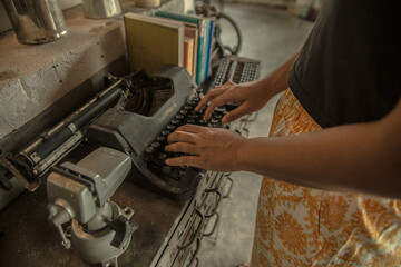an asian woman hands typing on an old typing machine