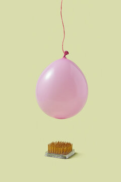 Pink balloon hanging on rope over sharp nails in studio