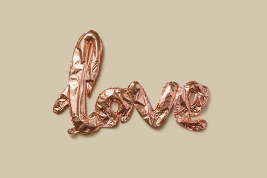 Composition of shiny balloons demonstrating love word on wall