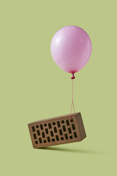 Pink gel balloon lifting up attached clicker brick in studio