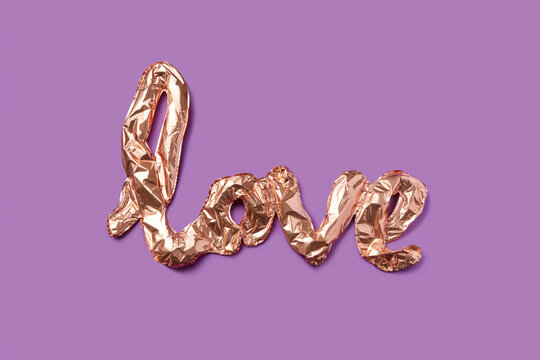 Golden foil balloons in shape of letters creating love inscription