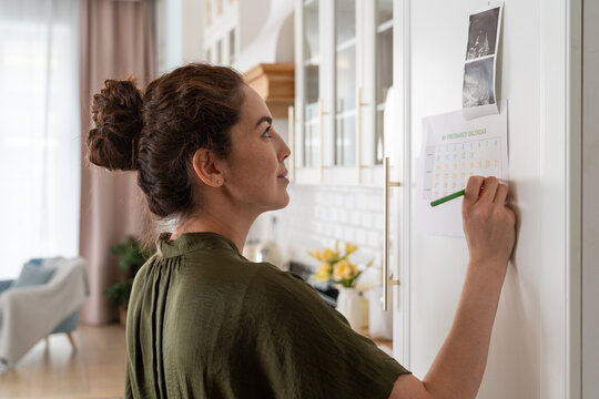 Woman Updating Pregnancy Calendar in Kitchen