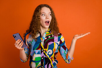 Photo of excited funny cute girl user wear stylish print clothes wow offer look empty space isolated on orange color background