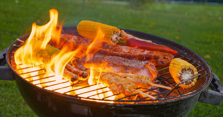 CLOSE UP: Roasted meat and vegetables and flared up fire flames on the grill © helivideo