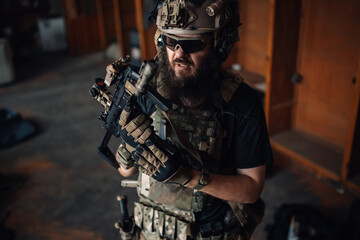 Portrait of bearded airsoft player putting magazine into rifle.