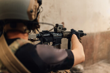 Rear view of air soft player with rifle going in action in crashed building