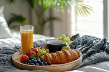 In the bedroom, a breakfast tray on the bed with croissants, cappuccino, orange juice and berries representing a romantic setting for breakfast.